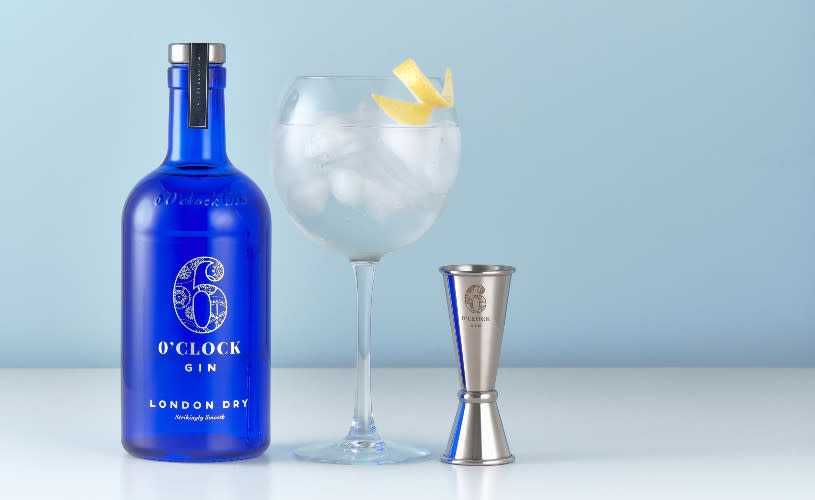 A blue gin bottle next to a gin glass and a spirit measure - Credit Bramley and Gage