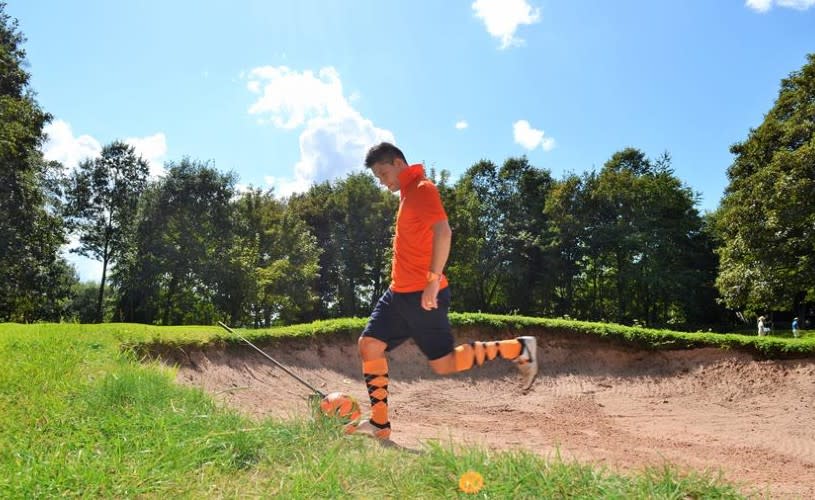 A man wearing an orange football kit playing footgolf - Credit Ashton Court
