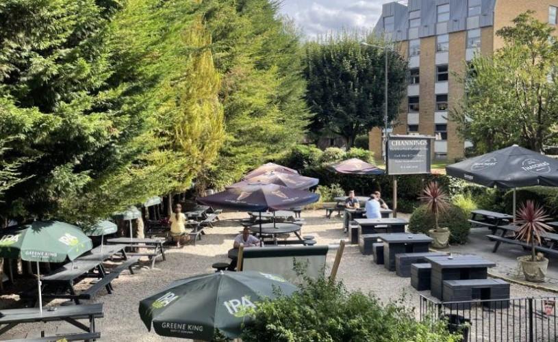 Large empty pub garden surrounded by trees