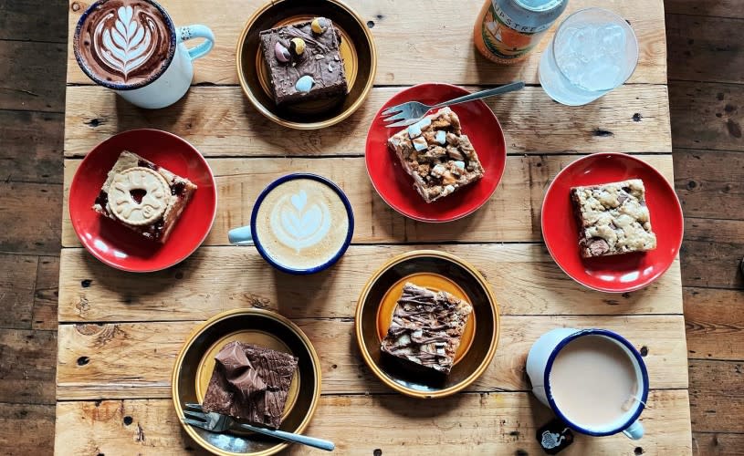 Various cakes and mugs of hot drinks on a table at Orchard Coffee Co in St George, East Bristol - credit Orchard Coffee Co