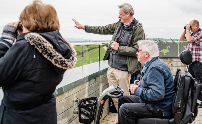 A wheelchair user birdwatching with family on the accessible estuary tower at WWT Slimbridge near Bristol - credit WWT Slimbridge Wetland Centre