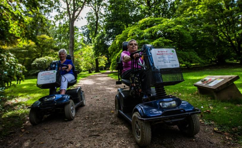 Two mobility scooter users on a path at Westonbirt Arboretum - credit Johnny Hathaway