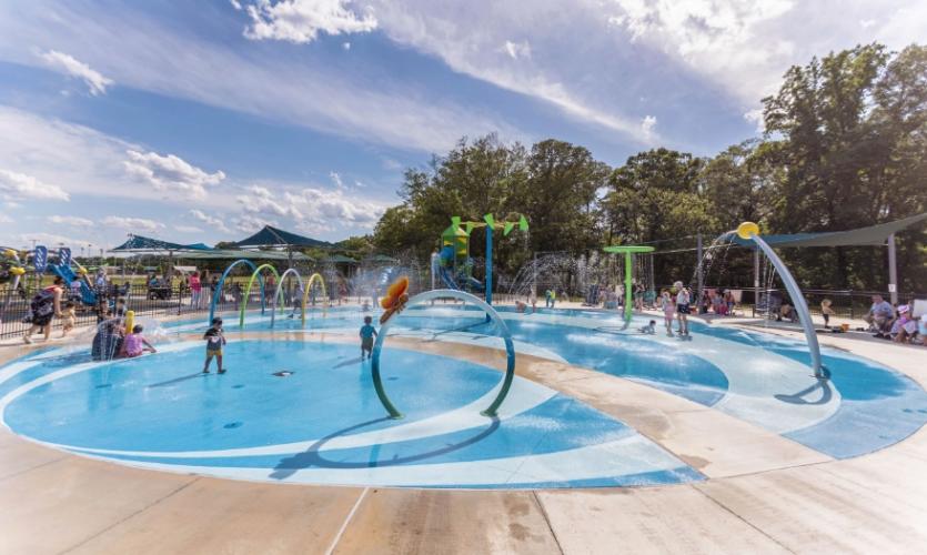 A concrete splash pad with overhead fountains, waterfalls, hoops, and other attractions!