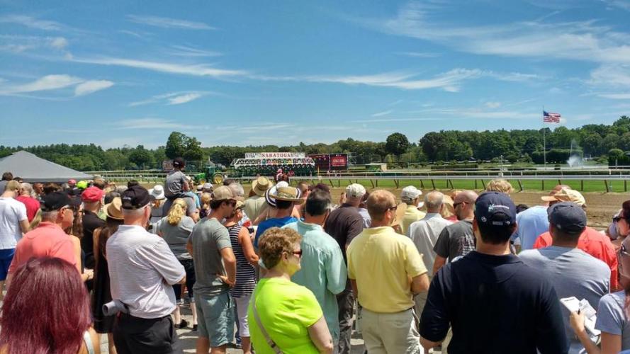 Crowd of people standing by the fence at the track