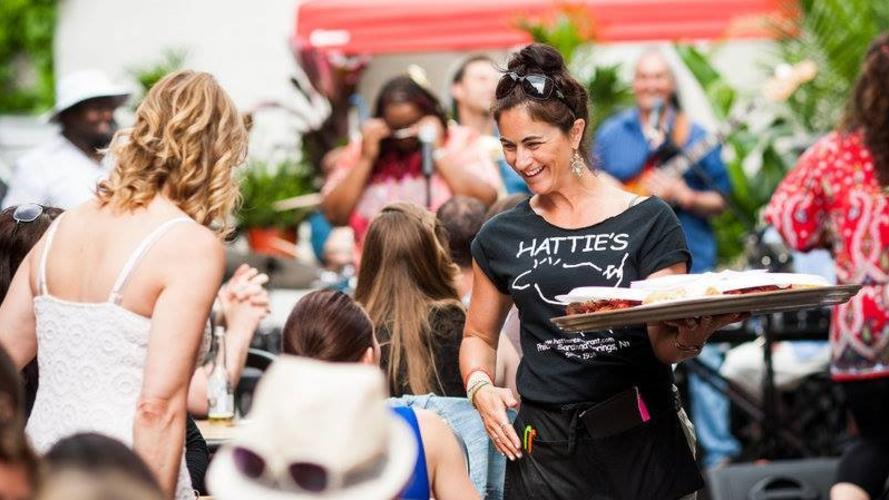 Waitress smiling at diners on crowded patio during Crawfish Fest