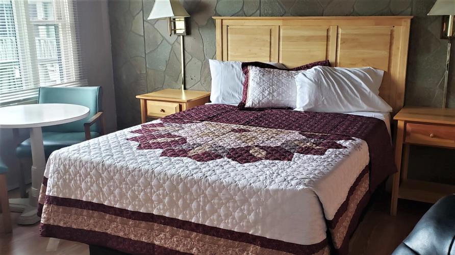 Large bed with light-wood headboard and quilt