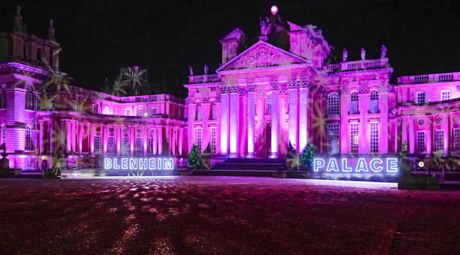 Blenheim Palace lit up in pink with the words Blenheim Palace in lights for festive celebrations