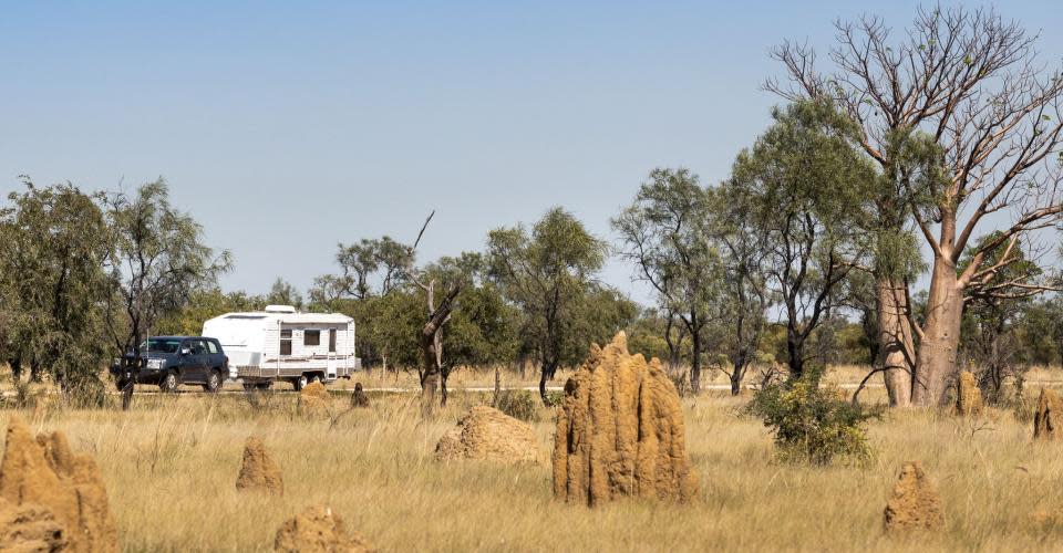 Car and Caravan on Derby Highway with termite mounds in foregound. Image Taryn Yeates Photography, Australia's North West Tourism