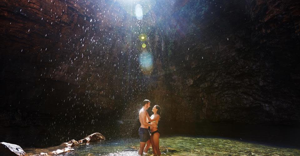 two people standing under a waterfall, Kimberley waterfalls