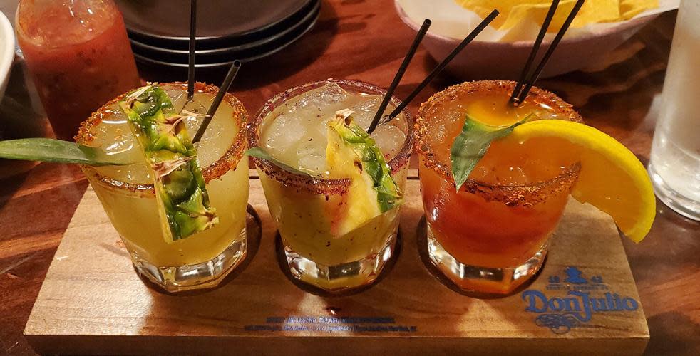 A margarita flight of 3 small glasses with slices of fruit