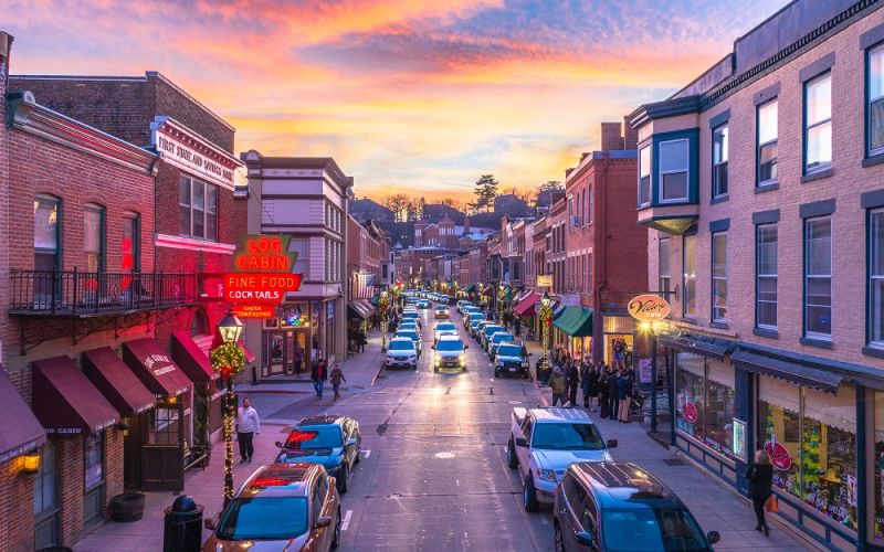 Candlelit luminaria bags lining a snowy Galena street at dusk