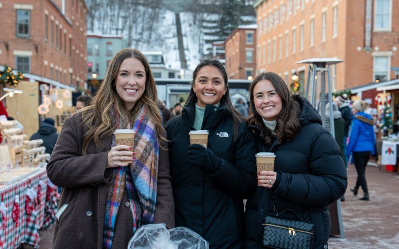 Friends with hot drinks at the Holidaze Festival holiday market in downtown Galena