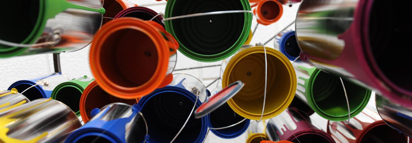 Art installation of multi-colored paint cans hanging from ceiling, photographed from below