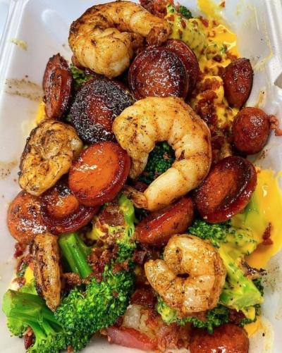 Baked potato covered in shrimp, hot links, cheese and broccoli