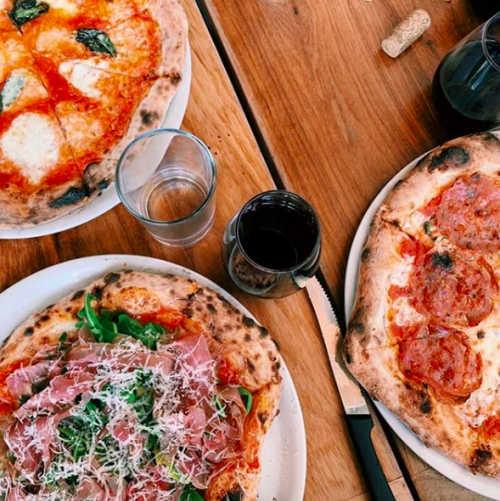 Three pizzas on a wooden table from Nomad Pizza