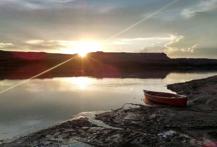 Canoe on the shore of the Green River with a sunrise in the background