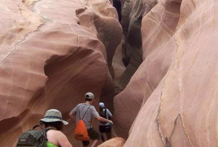 Hikers descending down a narrow slot canyon in southern Utah near the Four Corners area.