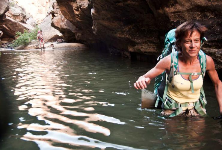 Female Hiker wading in deep water through slot canyon