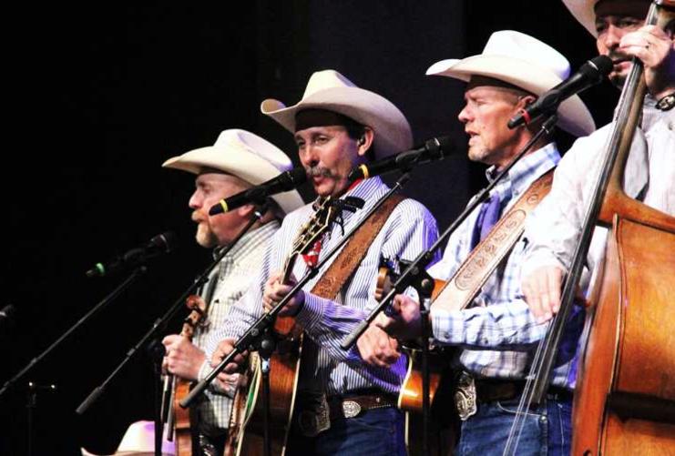 Four country western musicians on stage in white hats