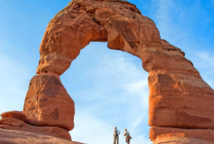 Two people standing under Delicate Arch