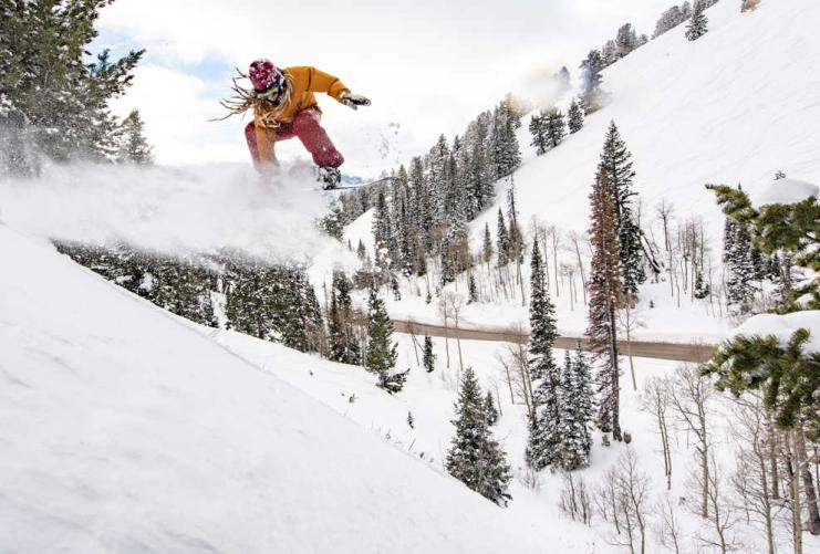 Snowboarder jumping down a steep slope