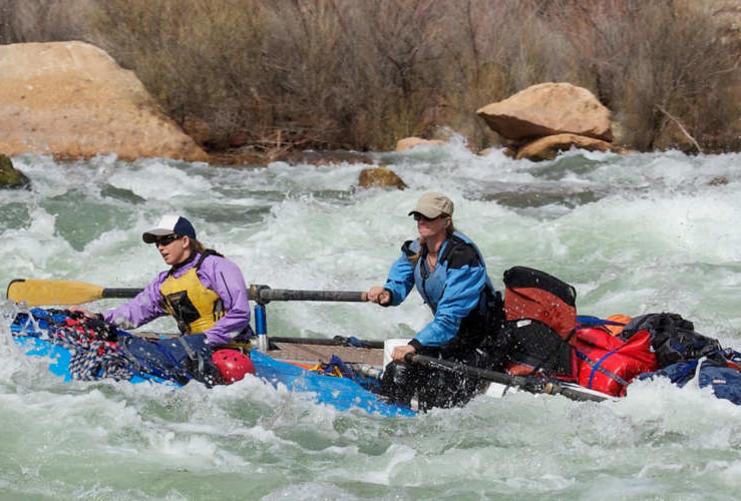 Two women on a raft passing down rapids