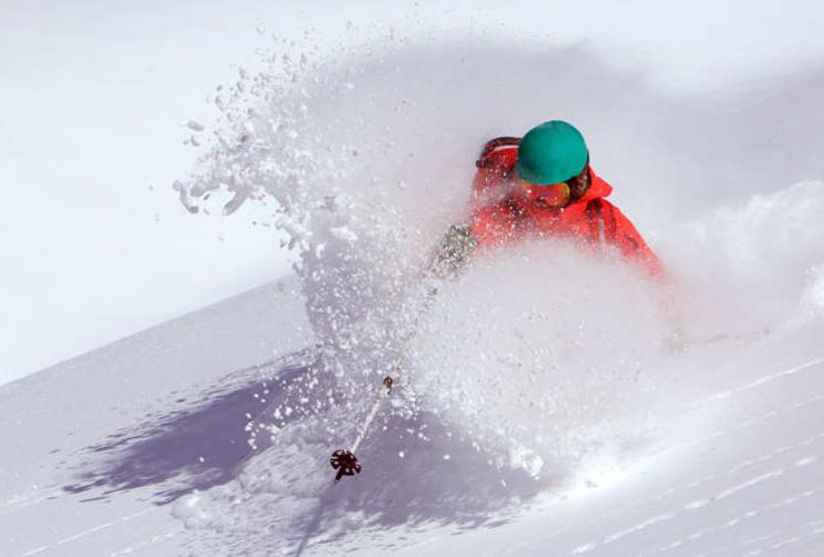 Skier carving through deep powder on a sunny day