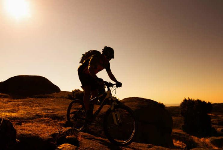 Mountain biker going down slick rock at sunset