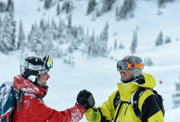 Two skiers shaking hands on a ski slope