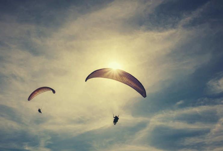 People paragliding in the sunset