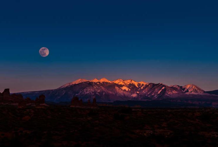 Mountains at sunset in Arches with moon behind
