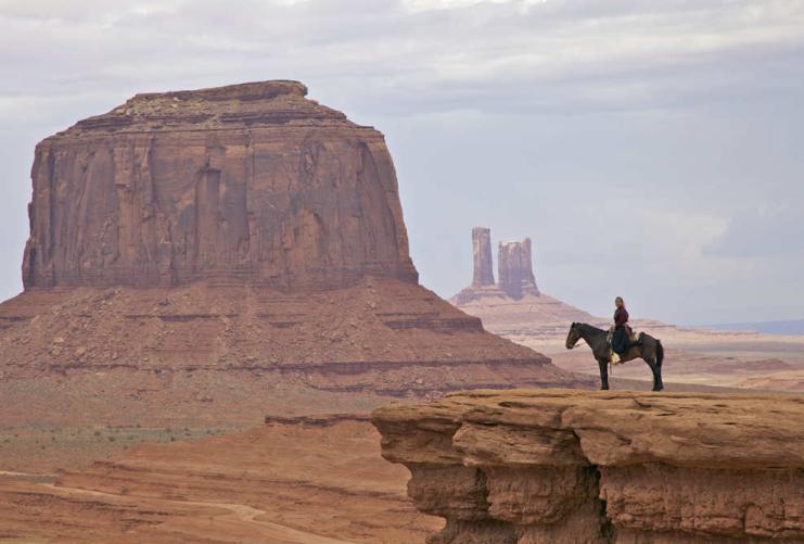 Desert landscape photo of Monument Valley with horseback rider