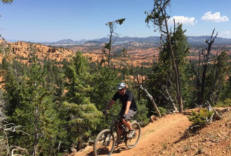 Male mountain biker riding on the Thunder Mountain Trail with valley below him