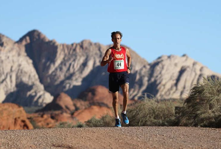 Distance runner in a red jersey with St. George mountains in the distance