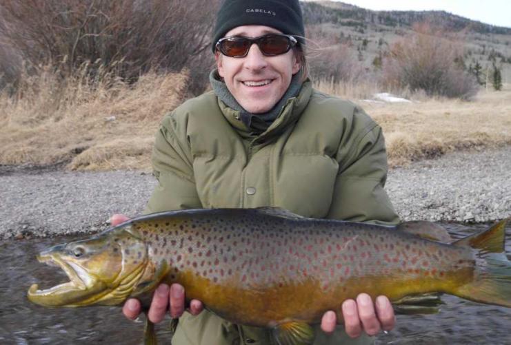Man holding a large fish in a mountain river