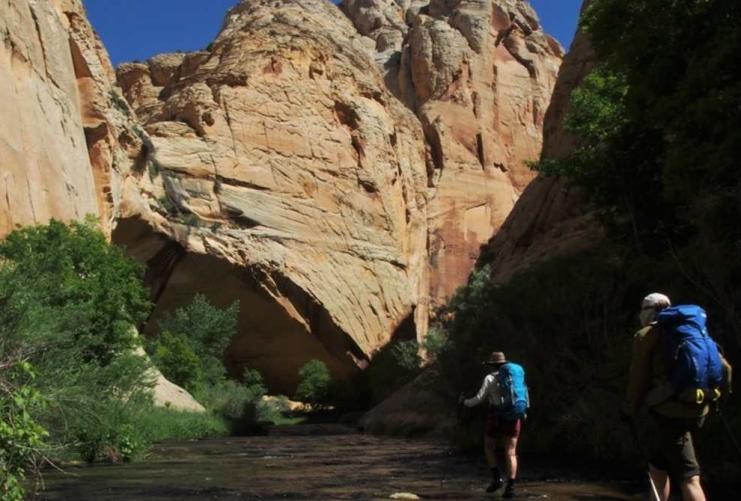 Two hikers walking through river in southern Utah