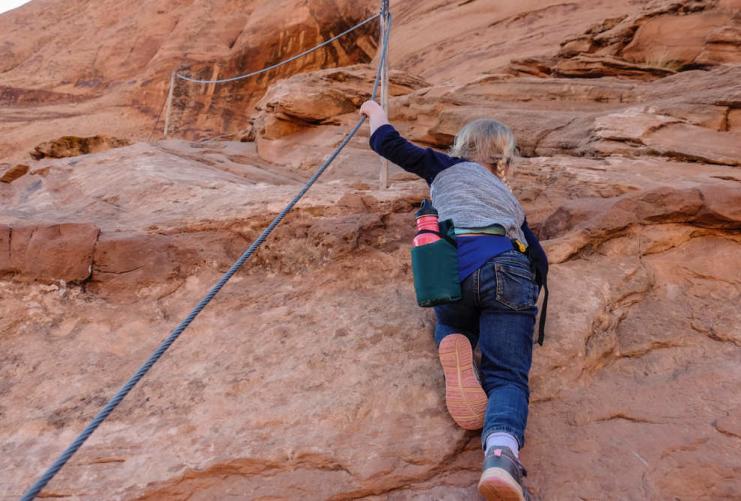 Girl using hiking cable on Corona Arch Hike
