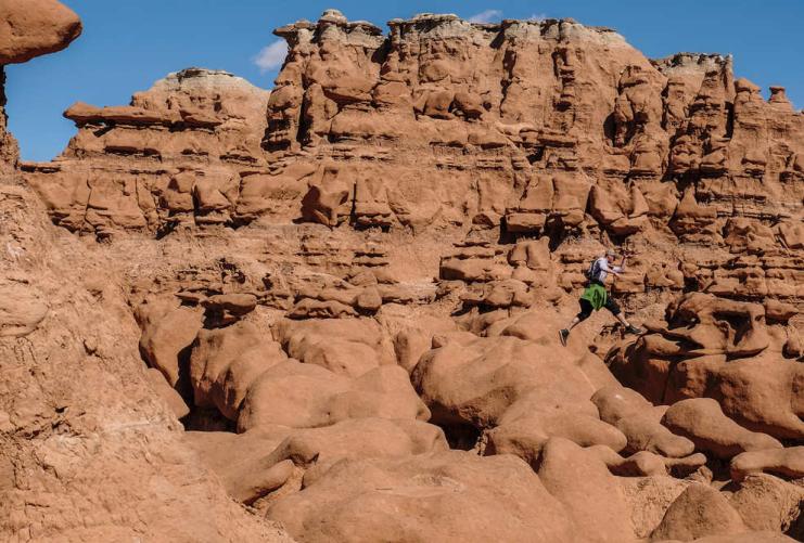 Hiker jumping between rocks in Goblin Valley Utah