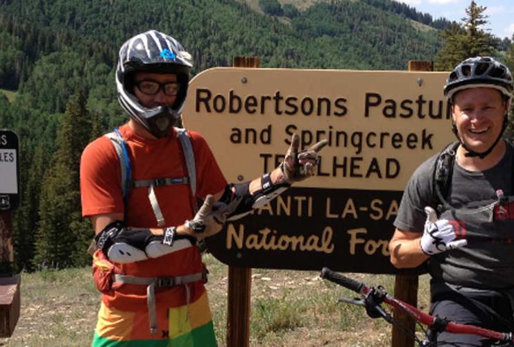 Two mountain bikers posing in front of Robertsons Pasture and Springcreek Trailhead