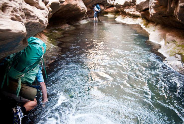 Backpacker wading through slot canyon in Grand Staircase area