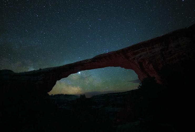 Natural bridge at night with bright stars