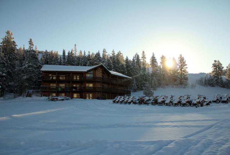 Beaver Creek Lodge with a line of snowmobiles in the winter with snow.