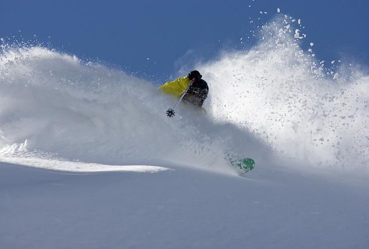 Skier in yellow jacket skiing through deep powder in Salt Lake City, Utah