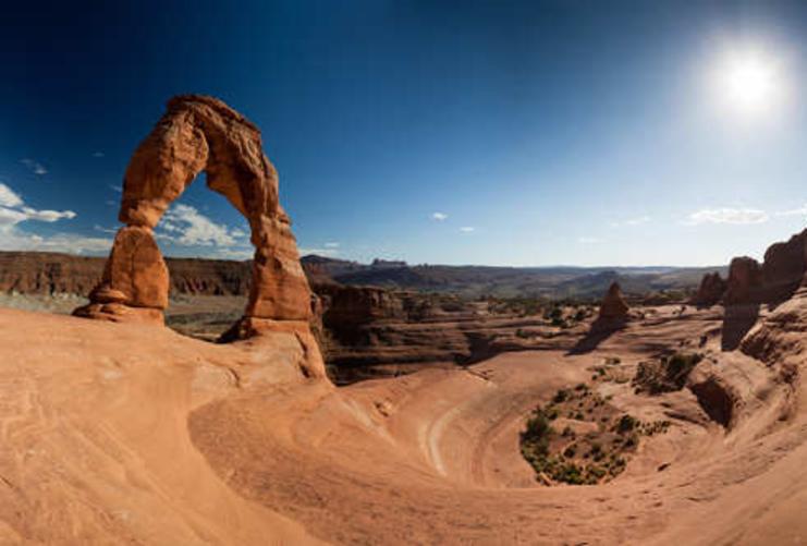 Picture of delicate arch with the sun high in the sky on a summer day