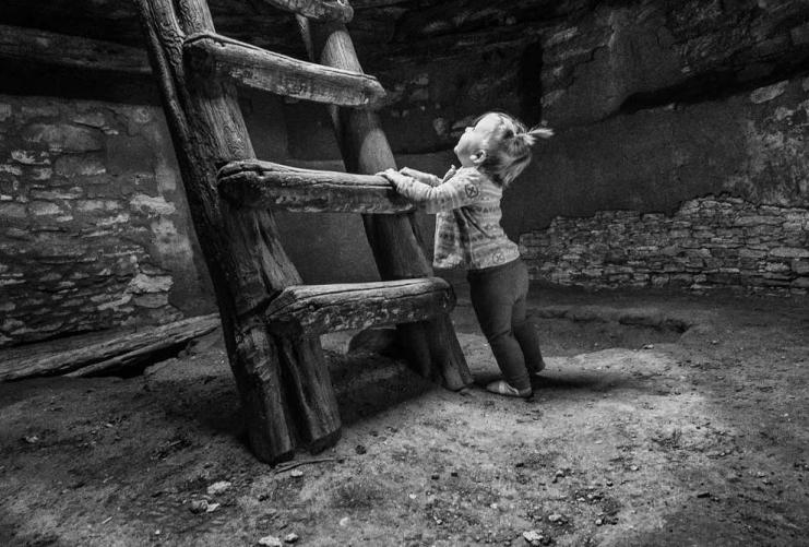 Toddler touching the ladder on the inside of a Native American ruin