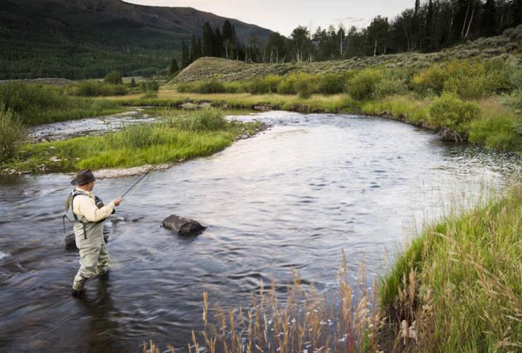 Man standing in river fly fishing