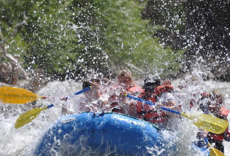 Group of people white water rafting down rapids on a Utah river.