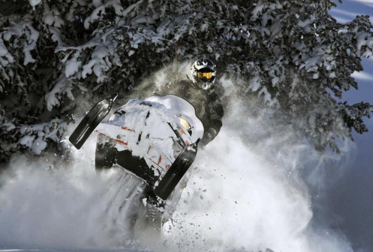 Snowmobile rider driving through deep snow