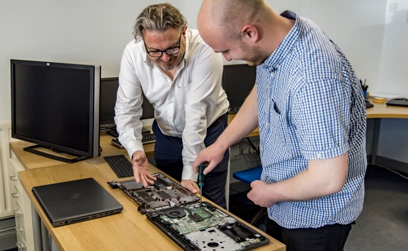 Two men working on the circuit board of an open computer - credit goto IT