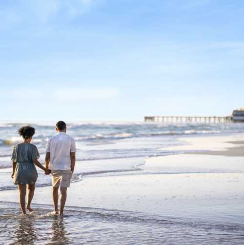 Couple walking on the beach by the pier